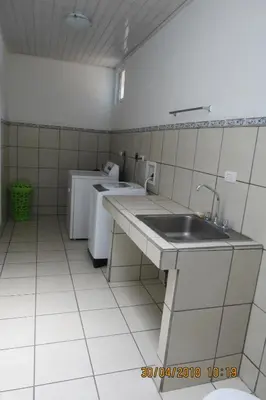 a white tiled kitchen with a sink and a counter at Apto D Laidman y Raabe SRL in Mercedes
