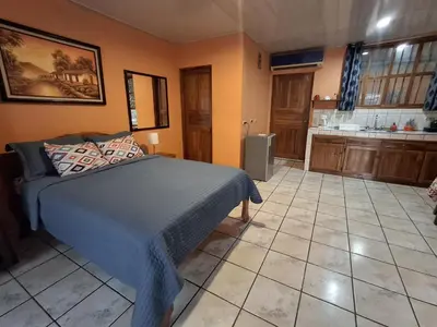 a bedroom with a bed and a kitchen at Apartamentos Quepos Malichita Studio in Quepos
