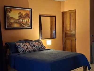 a bedroom with a blue bed and a mirror at Apartamentos Quepos Malichita Studio in Quepos