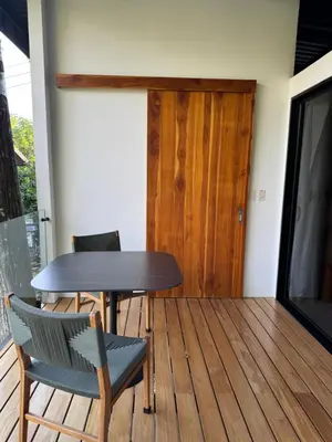 a table and chairs on a wooden deck with a door at Casa Rucca in Uvita