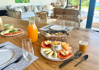 a wooden table with plates of food and orange juice at Pandanus Lodge & Retreats Bungalow Strelizia in San Ramón