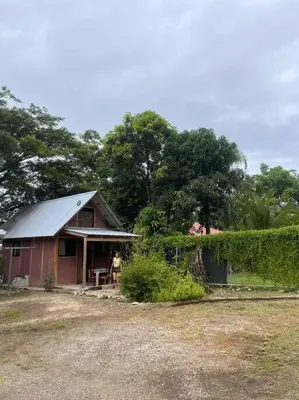 a small red house with a man standing outside at Nosara Hemp House in Nosara