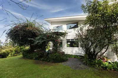 a white house with a window in a yard at Refugio Monteverde house, privacy & ocean view! in Monteverde Costa Rica