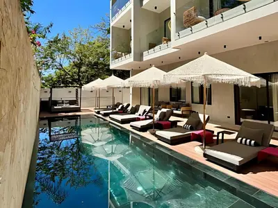 a pool with chairs and umbrellas next to a building at Blooma Boutique Hotel in Santa Teresa Beach