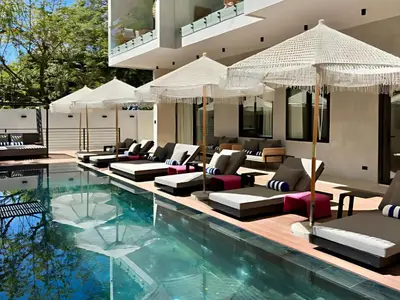 a swimming pool with lounge chairs and umbrellas at Blooma Boutique Hotel in Santa Teresa Beach