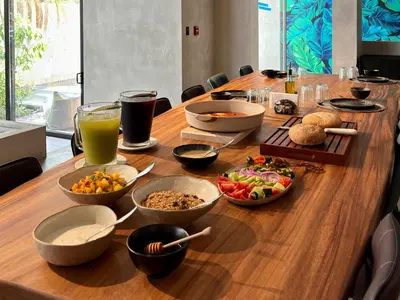 a long wooden table with bowls of food and drinks at Blooma Boutique Hotel in Santa Teresa Beach
