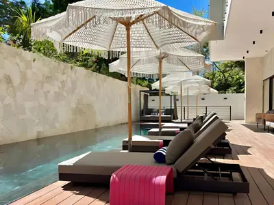 a pool with several lounge chairs and umbrellas at Blooma Boutique Hotel in Santa Teresa Beach