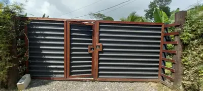 a metal garage door with a wooden gate at La dulce Casita in Uvita