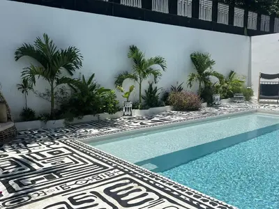 a swimming pool next to a building with palm trees at Desiree Luxury Apartamentos in Santa Teresa Beach
