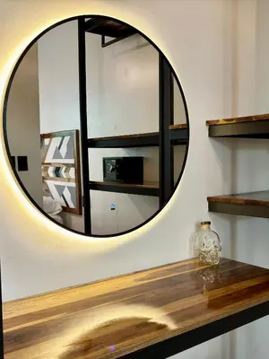 a round mirror on a wall with a wooden counter at Desiree Luxury Apartamentos in Santa Teresa Beach