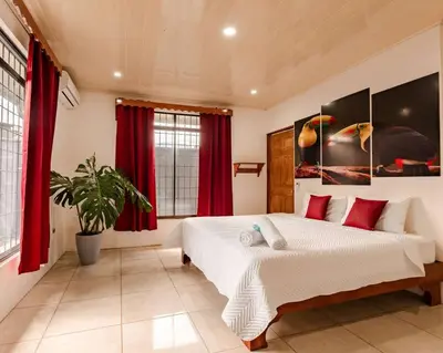a bedroom with a large bed with red curtains at Gaby's Home In Downtown La Fortuna in Fortuna