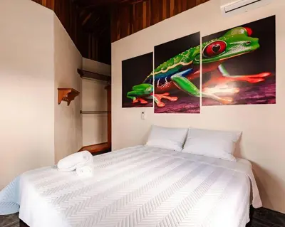 a bedroom with a bed with three paintings on the wall at Gaby's Home In Downtown La Fortuna in Fortuna