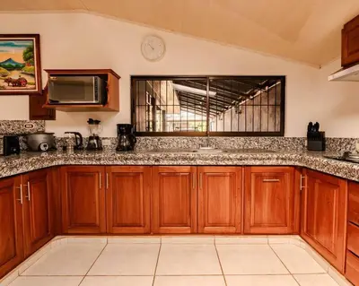 a large kitchen with wooden cabinets and a window at Gaby's Home In Downtown La Fortuna in Fortuna