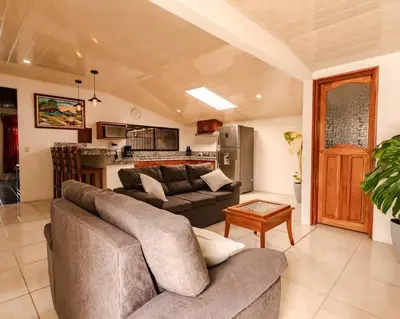 a living room with a couch and a kitchen at Gaby's Home In Downtown La Fortuna in Fortuna