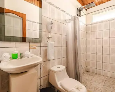 a white bathroom with a toilet and a sink at Gaby's Home In Downtown La Fortuna in Fortuna