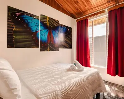a bedroom with a butterfly painting on the wall at Gaby's Home In Downtown La Fortuna in Fortuna