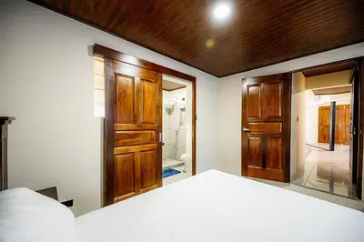 a bedroom with a bed and wooden doors and a bathroom at Arenal Summit in Nuevo Arenal