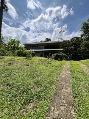 a house on top of a grassy hill with a building at Hospedaje Santiago in Sarapiquí