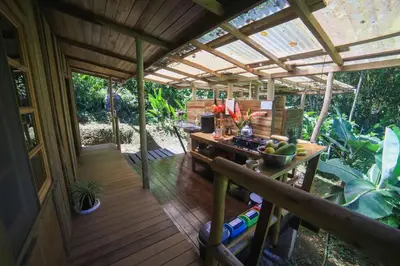 an outdoor kitchen with a wooden deck with a table at Preciosa Cabaña de Montaña in Turrialba