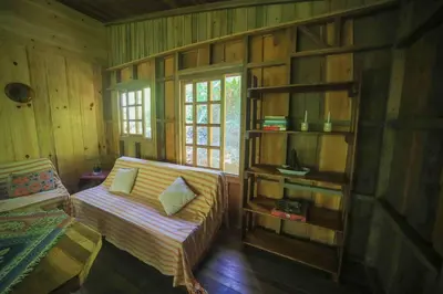 a living room with a couch and a book shelf at Preciosa Cabaña de Montaña in Turrialba