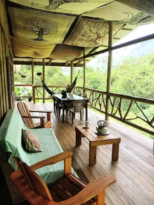 a living room with a table and chairs on a porch at Preciosa Cabaña de Montaña in Turrialba