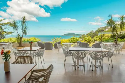 a patio with tables and chairs and the ocean at Wyndham Tamarindo in Tamarindo