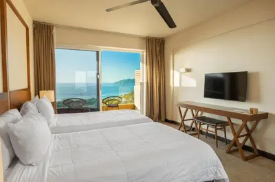 a bedroom with a bed and a desk and a television at Wyndham Tamarindo in Tamarindo