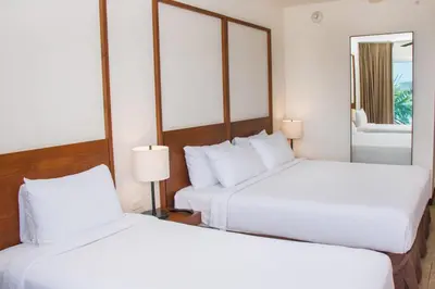 two white beds in a hotel room with a mirror at Wyndham Tamarindo in Tamarindo