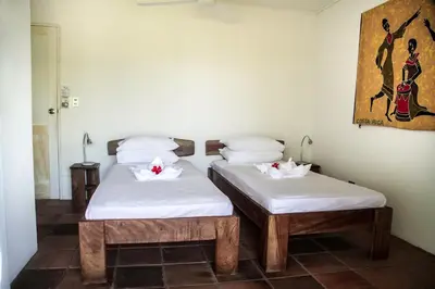 two beds in a room with white sheets at Hotel Horizontes de Montezuma in Montezuma
