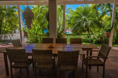 a wooden table and chairs on a patio with palm trees at Hotel Horizontes de Montezuma in Montezuma