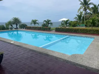 a large blue swimming pool with the ocean in the background at Sea view Apartment in Puerto Limón