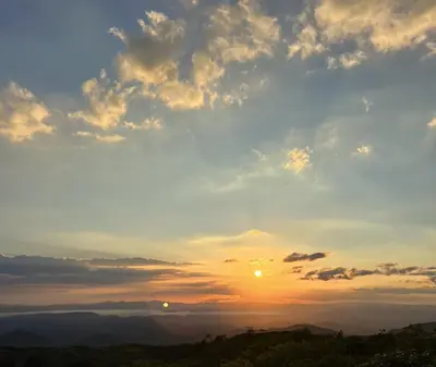 a sunset with the sun setting over the mountains at Golden Sunset Glamping in Monteverde Costa Rica