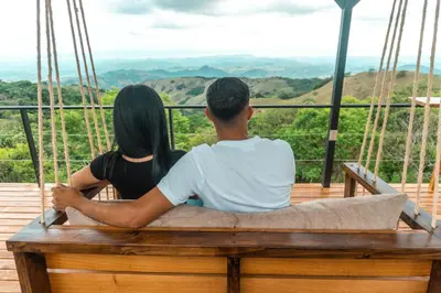 a man and a woman sitting on a swing at Golden Sunset Glamping in Monteverde Costa Rica