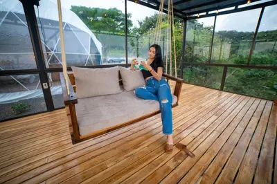 a woman is sitting on a porch swing at Golden Sunset Glamping in Monteverde Costa Rica