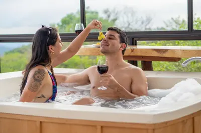 a woman giving a man a glass of wine in a bathtub at Golden Sunset Glamping in Monteverde Costa Rica