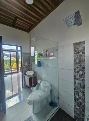 a bathroom with a toilet and a glass shower at Casa Tigrillo - La Fortuna in Agua Azul