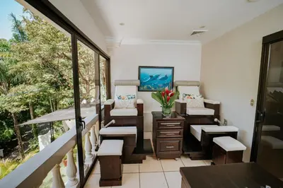 a balcony with chairs and a desk and windows at Vista Suites at Parador - Adults Only in Manuel Antonio