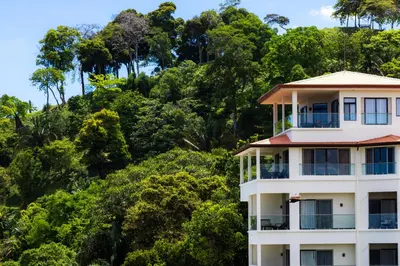 a building with trees in the background at Vista Suites at Parador - Adults Only in Manuel Antonio