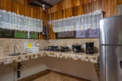 a kitchen with a refrigerator and a sink and windows at Hospedaje Rancho mi Tata in Solania