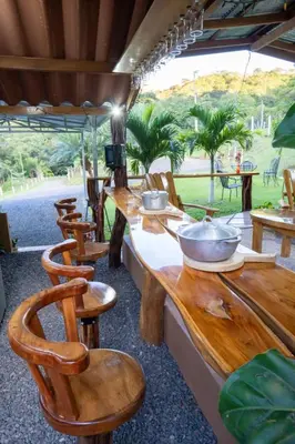 a restaurant with wooden tables and chairs with a view of a field at Hospedaje Rancho mi Tata in Solania