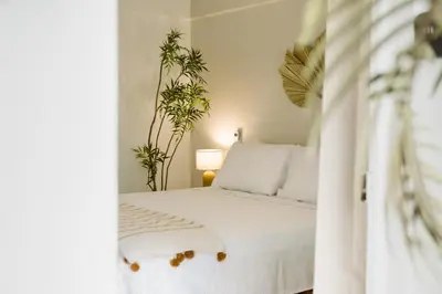 a bedroom with a white bed with two plants at Hotel VillaFlores in Quesada