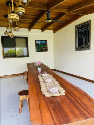 a large wooden table in a room with flowers on it at Casa 1856- cómodas habitaciones en el Centro de Alajuela in Alajuela City