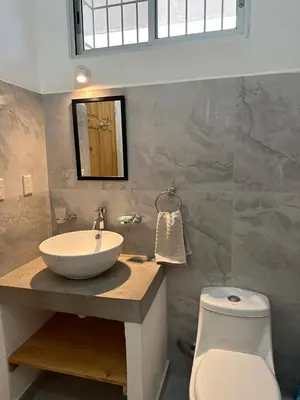 a bathroom with a sink and a toilet and a mirror at Hotel Bella Tamarindo Guanacaste in Tamarindo