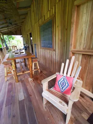a wooden porch with a wooden table and chairs at Papaya Lodge in Bijagua