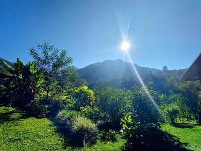 a sun shining on a mountain with a green field at Aloha chirripo cabaña familiar in Convento