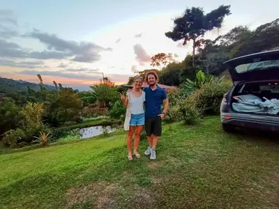 a man and a woman standing next to a car at Aloha chirripo cabaña familiar in Convento