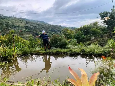 a man standing next to a body of water holding a rod at Aloha chirripo cabaña familiar in Convento