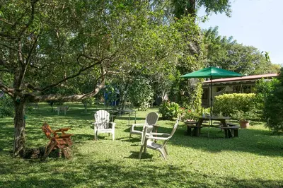 a yard with chairs and a table and an umbrella at Airport Costa Rica B&B in Alajuela City