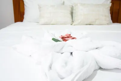 a bed with white towels and a rose on it at Casa DesKanso - La Fortuna in Fortuna
