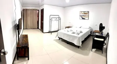 a white bedroom with a bed and a table at Marianas Apartments 5MIN SJO AIRPORT in Alajuela City